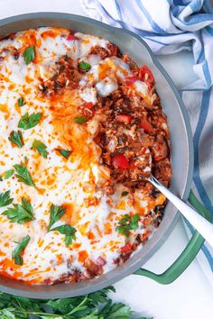 a casserole dish with meat, cheese and vegetables in it on a blue and white towel