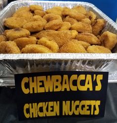 some chicken nuggets are in a metal pan on a table with a sign that says chewbaca's chicken nuggies