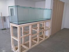 a fish tank sitting on top of a wooden shelf next to a wall in an empty room