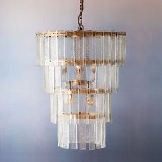 a glass chandelier hanging from a chain on a blue wall in a room