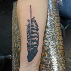 a black and white feather tattoo on the right arm, with an arrow in it