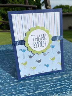 a thank you card sitting on top of a blue tablecloth with birds and stripes