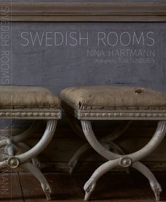 two white benches sitting next to each other in front of a gray wall with the words swedish rooms written on it