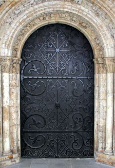 an ornate iron door in the middle of a stone building