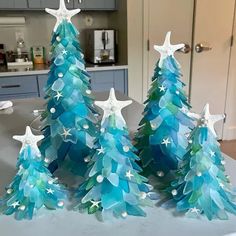 three christmas trees made out of blue and green paper with white stars on the top