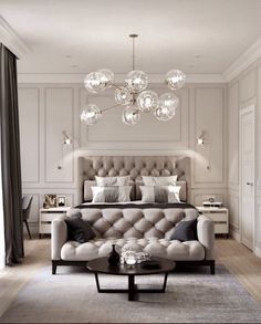 a bedroom with a bed, couch and chandelier