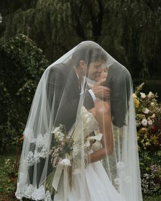 a bride and groom kissing under a veil