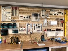 a workbench with many tools hanging on the wall and various other items displayed