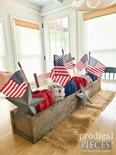 a wooden box filled with american flags on top of a hard wood floor next to windows