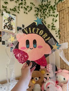 a person holding up a paper cutout with the word victory on it in front of stuffed animals