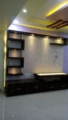 an empty room with some shelves and lights on the wall behind it is lit up by recessed lighting