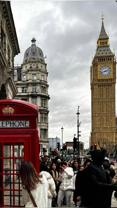 people are standing in front of a red phone booth with big ben in the background