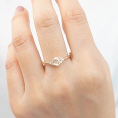 a woman's hand wearing a gold ring with two small white stones on it