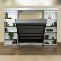 a white book shelf filled with lots of books next to a vase and potted plant