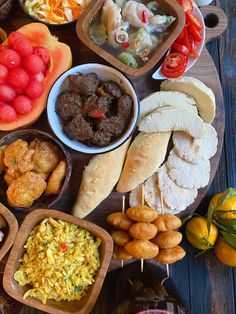 an assortment of food is displayed on a wooden platter, including meats and vegetables