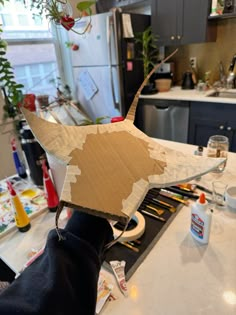 a dog is standing on the kitchen counter with its head in a cardboard box that has been cut out