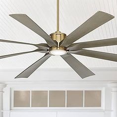 a ceiling fan that is hanging from the ceiling in a room with white walls and windows