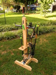 a wooden rack with many fishing rods on it in the grass next to a tree