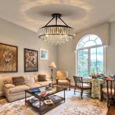 a living room filled with furniture and a chandelier hanging from the middle of it