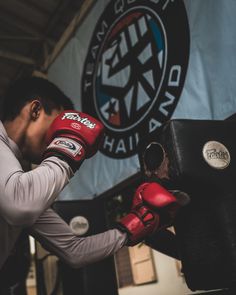 a man wearing red boxing gloves and holding his head in the air while standing next to a punching bag