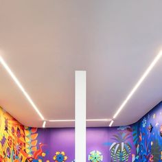 a room with colorful wallpaper and paintings on the walls is lit by recess lighting