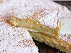 two pieces of cake sitting on top of a cooling rack covered in powdered sugar