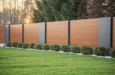 a large wooden fence in the middle of a grassy area with trees and bushes behind it