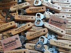 many wooden key chains are stacked on top of each other with name tags attached to them