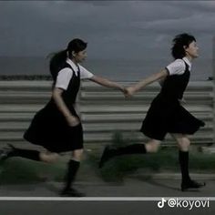 two women in black and white dresses are holding hands