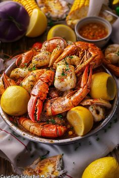 a plate full of lobsters, lemons and corn on the cob with garnishes