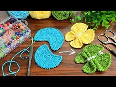 crocheted flowers and scissors are sitting on a table next to some yarns