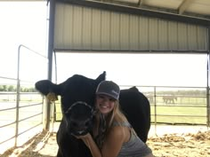 a woman is hugging a cow in a barn