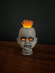 a creepy looking head with glowing eyes on a table