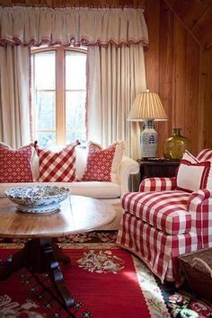 a living room with red and white checkered couches, coffee table and lamp