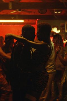 two people hugging each other in front of a group of people at a dance party