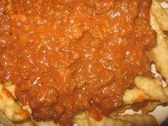 some kind of food that is on a white plate with red sauce and french fries