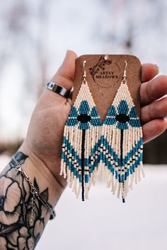 a person holding up a phone case with some tassels on it