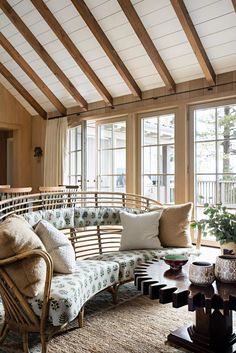 a living room filled with lots of furniture next to large window covered in wood beams