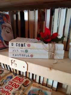 three books are stacked on top of each other in front of a book shelf filled with children's books