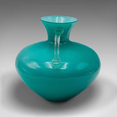 a green glass vase with a rope in the middle and water running through it's mouth