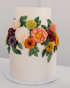 a white cake decorated with flowers and leaves