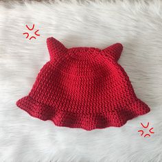 a crocheted cat hat laying on top of a white furnishing area