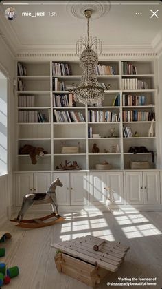 a room with bookshelves, rocking horse and toys on the floor in front of it