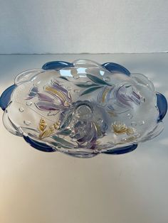 a glass bowl with flowers and leaves on it