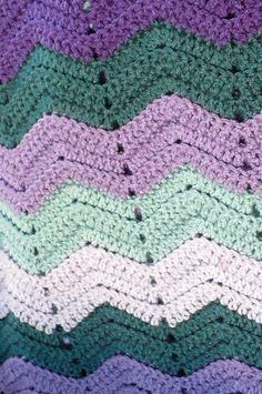 a crocheted blanket with purple, green and white stripes