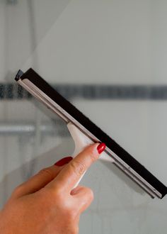 a woman's hand is holding onto the edge of a glass door with a black handle