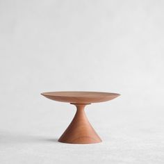 a small wooden bowl sitting on top of a white tableclothed flooring with a gray wall in the background