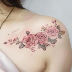 a woman's shoulder with pink roses on it and greenery around the breast