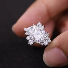 a close up of a person's hand holding a diamond ring