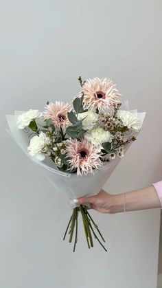 a person holding a bouquet of white and pink flowers